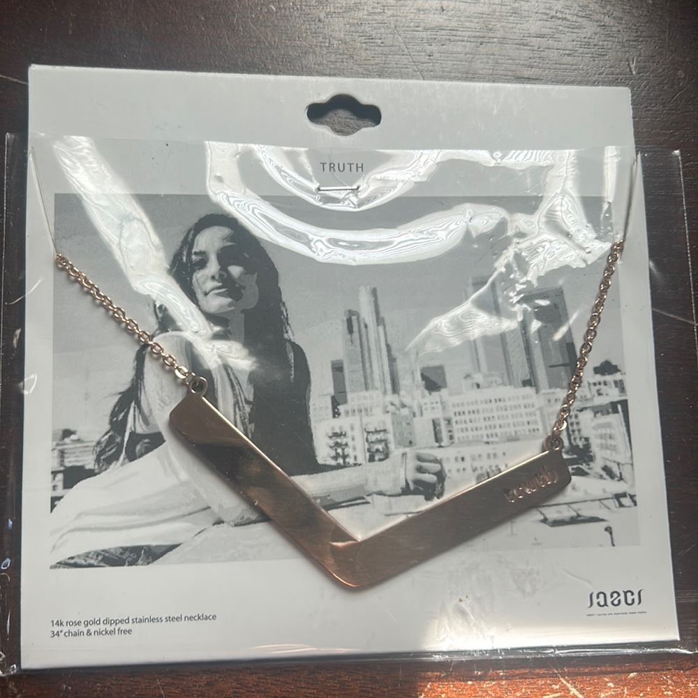 Long gold tone necklace with “truth” cutout
